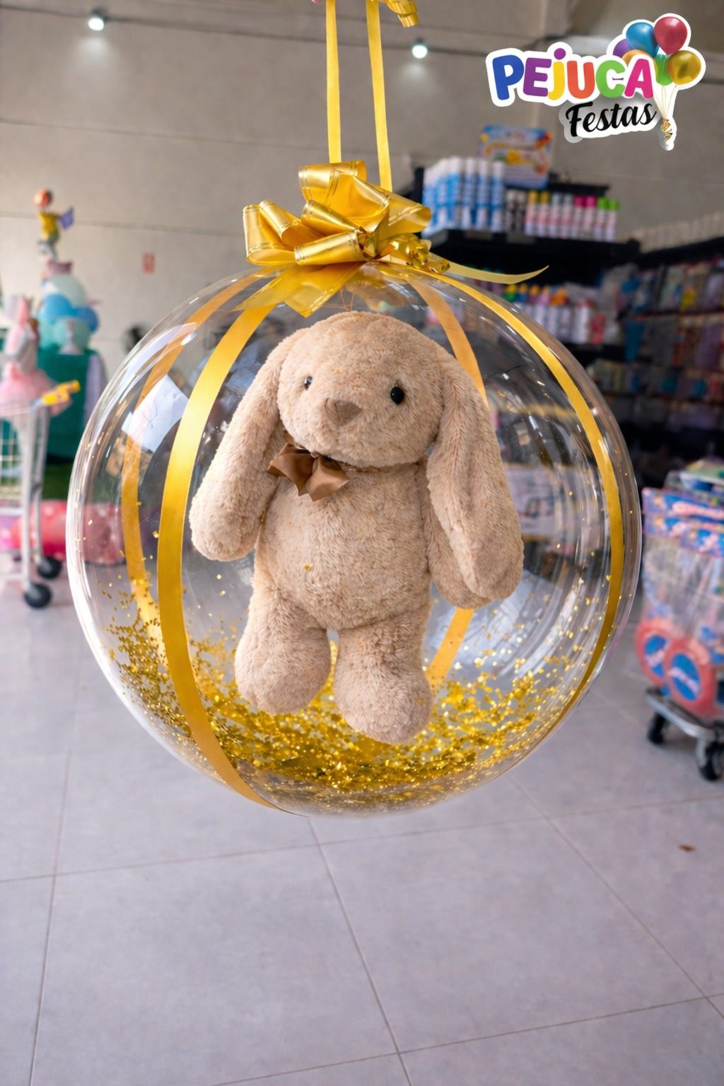 Balão bubble transparente com coelho pelúcia e dourado – Pejuca Festas Itanhaém Balão bubble gigante transparente com coelho de pelúcia dentro, fita dourada e confetes dourados, Pejuca Festas Itanhaém SP
